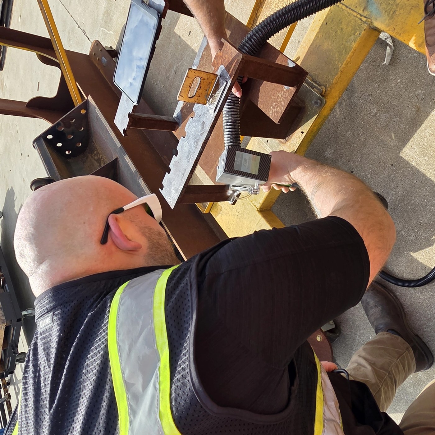 ALR technician laser-cleaning a steel bracket for weld preparation at JCB